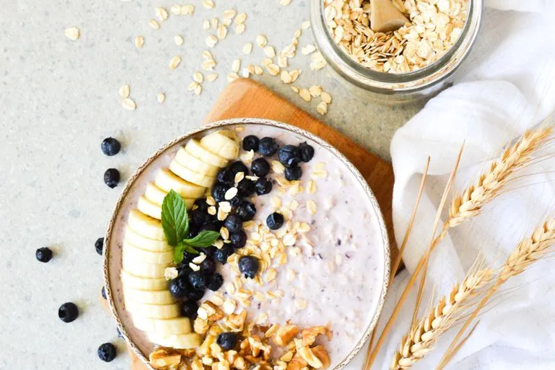 Bol de porridge garni de banane, de myrtilles et de noix, vu du dessus