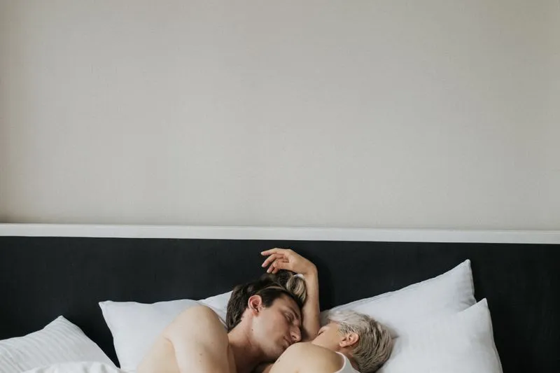 Couple allongé dans des draps blancs, éclairé par la lumière du matin