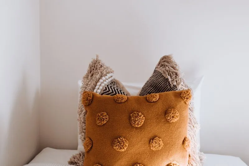 Plusieurs coussins de tailles différentes posés sur un lit aux draps blancs