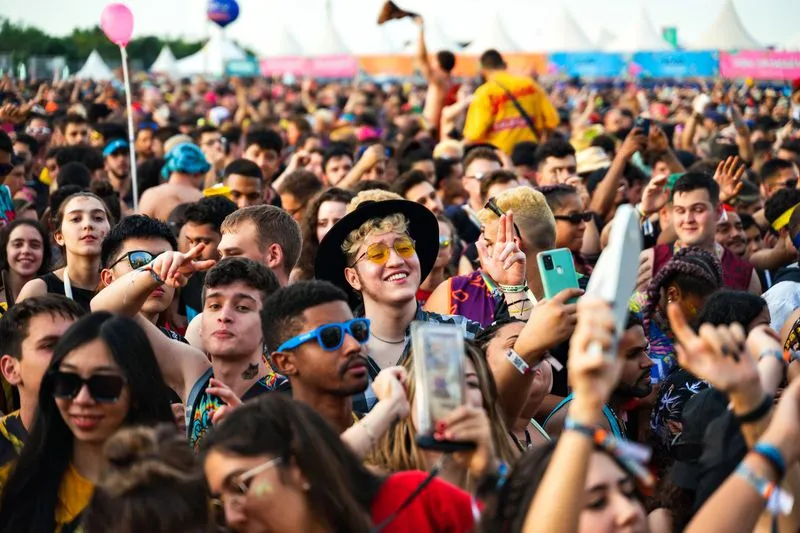 Foule dans un festival de musique en plein air, l'après-midi, avec plusieurs festivaliers en lunettes de soleil rondes et colorées