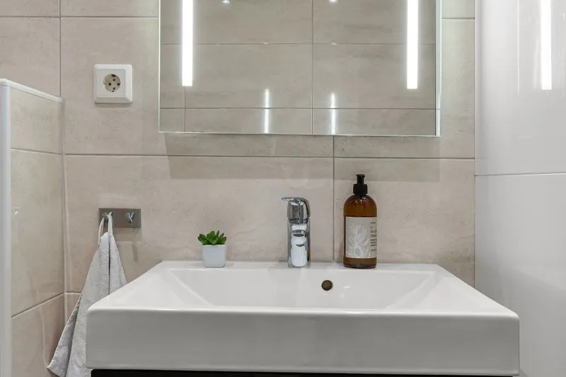 Miroir de salle de bains encadré de bandeaux lumineux LED de chaque côté, au-dessus d'un lavabo