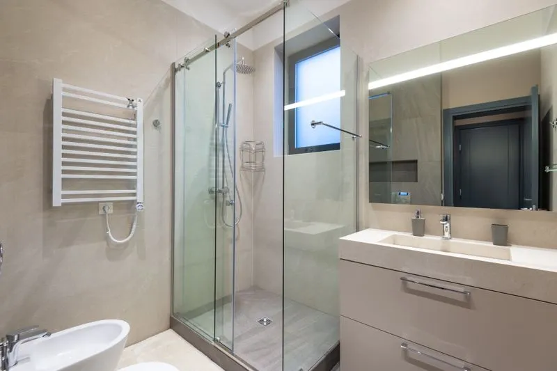Douche fermée par une paroi vitrée coulissante dans une salle de bains carrelée