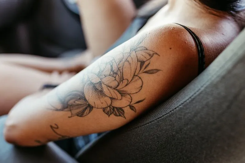 Avant-bras de femme portant un tatouage floral fin à l'encre noire