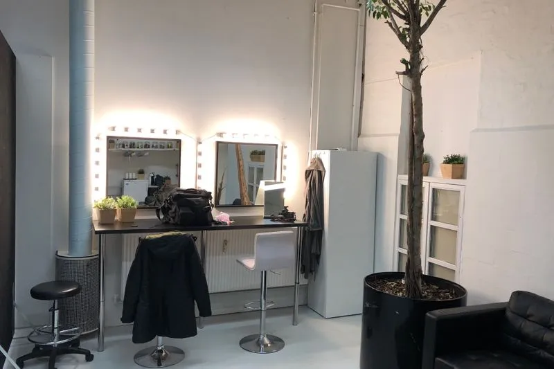 Loge de maquillage avec deux miroirs entourés d'ampoules et un plan de travail