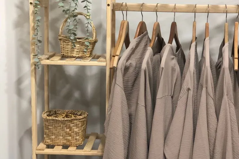 Portant chargé de vêtements aux couleurs neutres, chemises et vestes sur cintres
