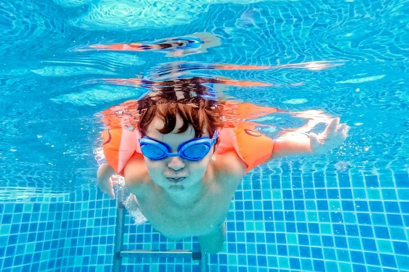 Enfant portant des brassards gonflables dans une piscine