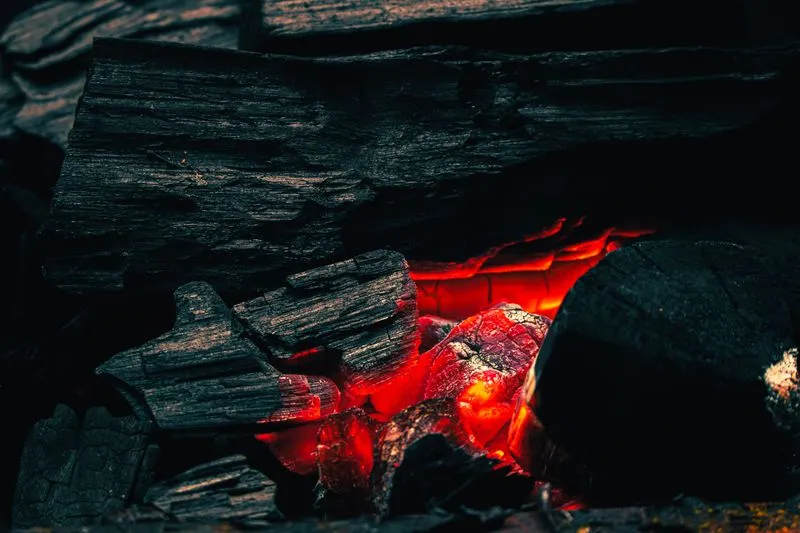Gros plan sur des braises de charbon incandescentes, d'un rouge profond, sans flamme visible