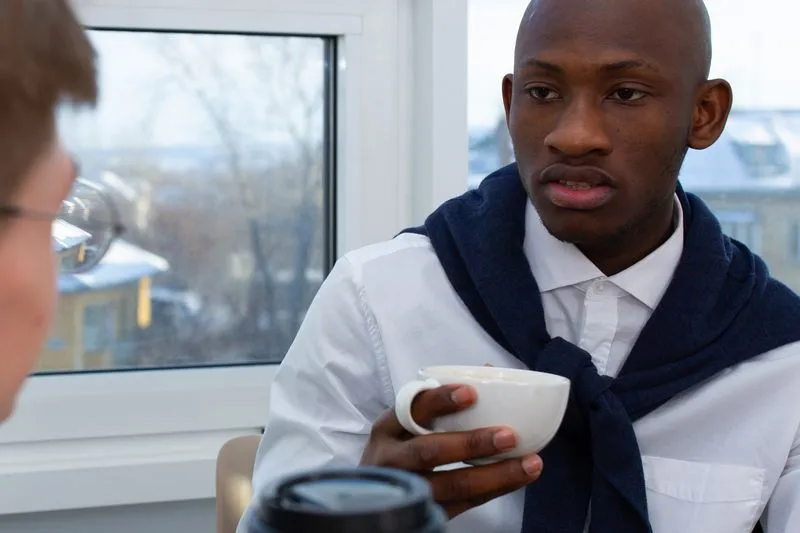 Deux collègues qui discutent autour d'un café, près d'une fenêtre lumineuse