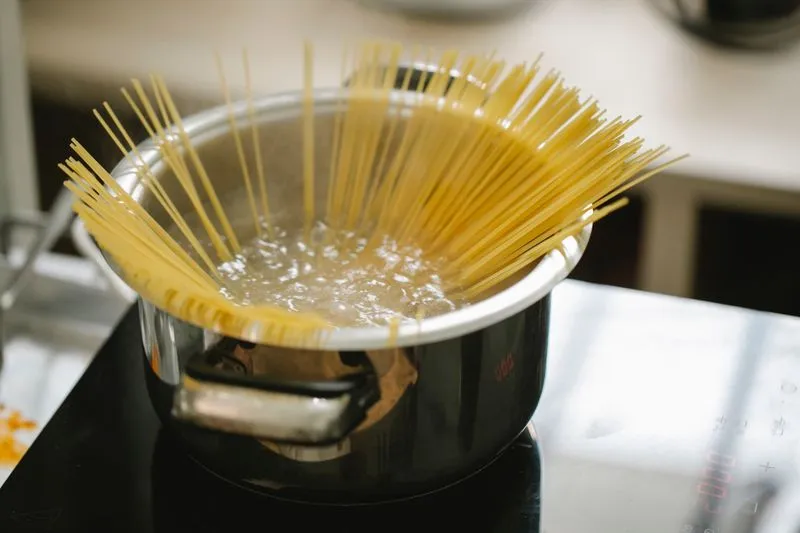 Spaghettis plantés dans une casserole d'eau bouillante, sur une cuisinière
