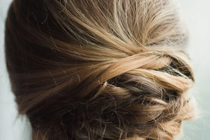 Gros plan de dos sur des cheveux méchés blonds, torsadés et rentrés à l'arrière de la tête