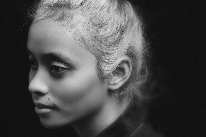 Profil d'une femme aux cheveux ramenés en arrière, quelques mèches folles autour du visage, en noir et blanc
