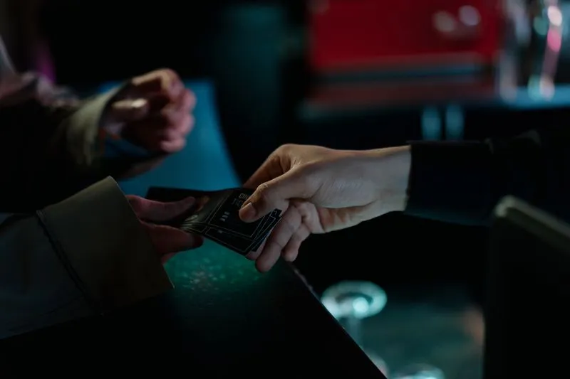 Gros plan sur l'échange d'un billet de cinéma entre les mains d'une cliente et d'un employé, au comptoir