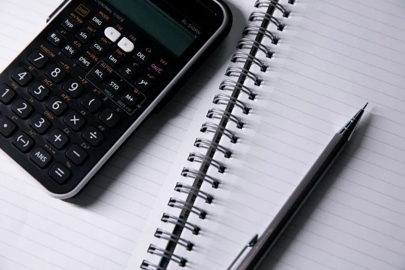 Carnet à spirale vierge, calculatrice et stylo posés sur une table