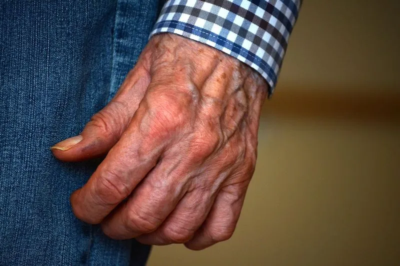 Main ridée d'une personne âgée, aux veines saillantes, posée sur un vêtement