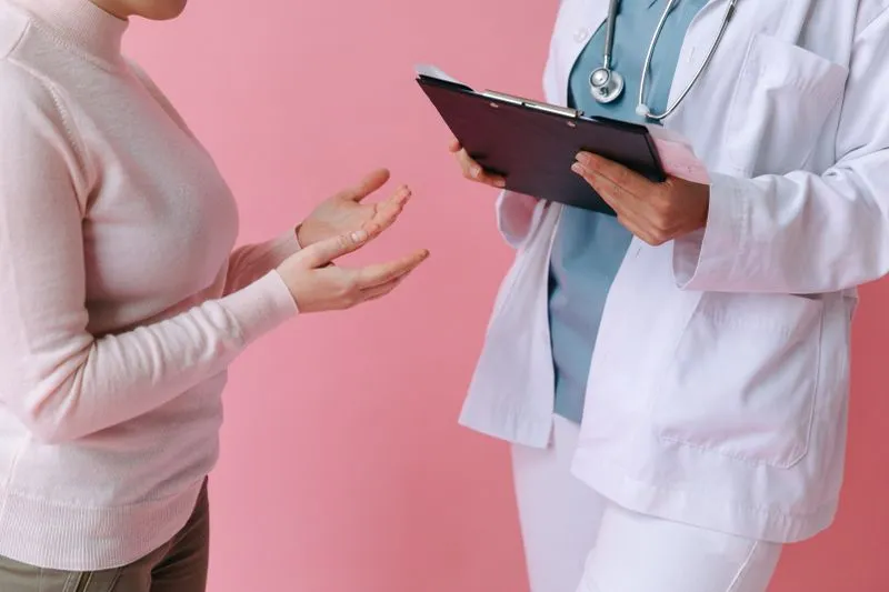 Une femme échangeant avec un professionnel de santé en blouse blanche, qui tient un dossier en main