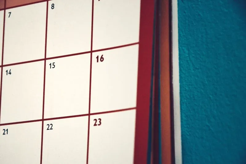 Gros plan sur un calendrier mural accroché au mur, avec la grille des jours du mois