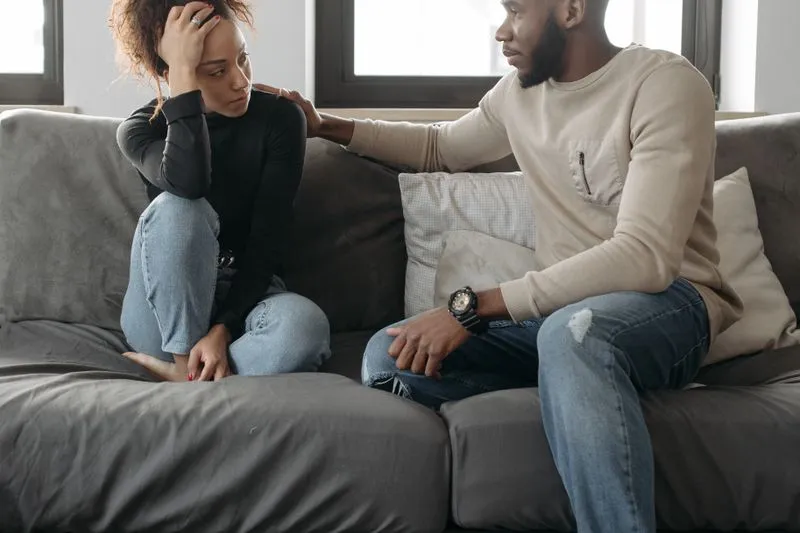 Jeune couple assis sur un canapé, tourné l'un vers l'autre, en pleine conversation sérieuse