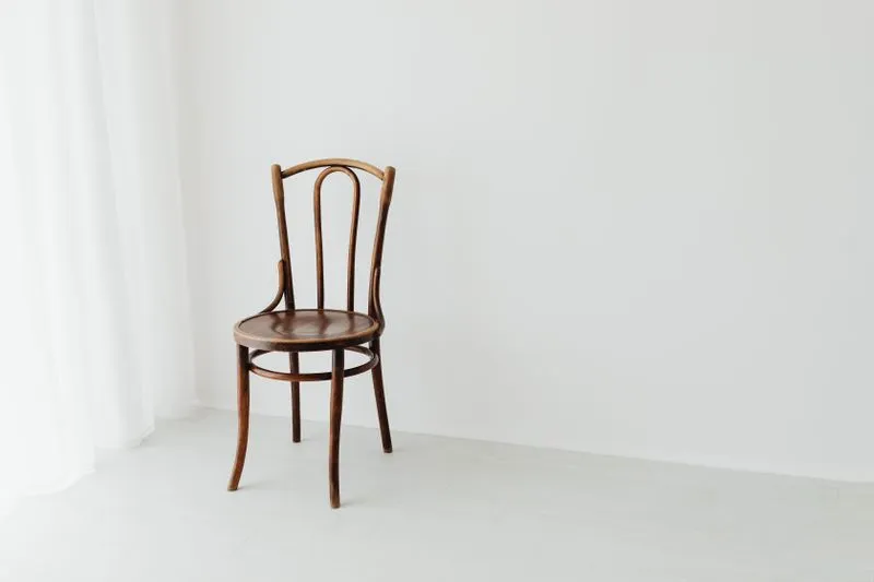 Chaise en bois sans accoudoirs dans une pièce lumineuse aux murs blancs