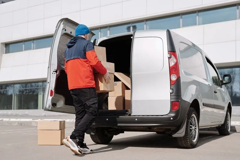 Un homme charge des cartons dans une camionnette utilitaire