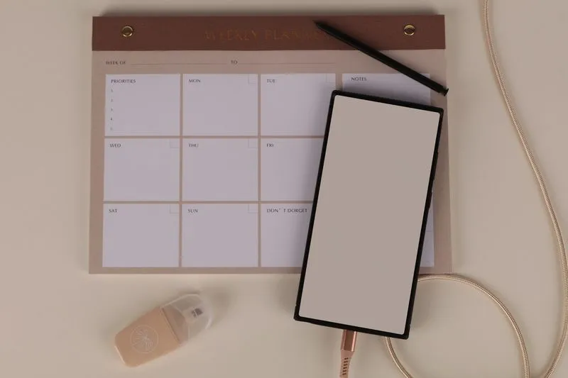 Planning hebdomadaire vierge, stylo et téléphone pour répartir les tâches du déménagement